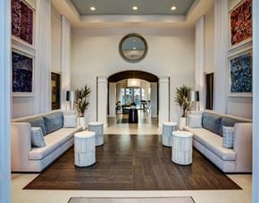 Pompano Beach apartment for rent - A spacious hallway with white couches and a large mirror on the wall.