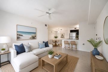 Homestead apartment for rent - A living room with a white couch, a coffee table, and a painting of a beach scene on the wall.