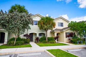 Homestead apartment for rent - a white house with palm trees in front of it