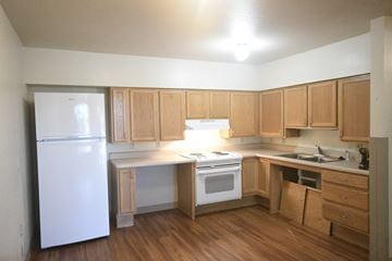 Roosevelt apartment for rent - an empty kitchen with wooden cabinets and a white refrigerator