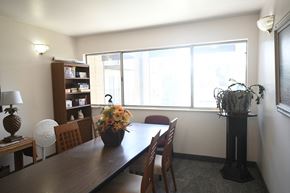 Sandy apartment for rent - a dining room with a wooden table and chairs and a large window