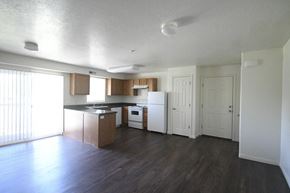 Heber City apartment for rent - an empty living room and kitchen with wood floors and white appliances