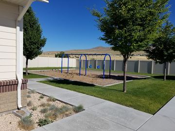 Tremonton apartment for rent - a playground in a yard with trees and a fence
