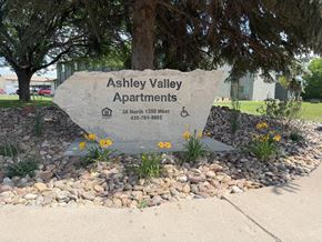 Vernal apartment for rent - A stone sign for Ashley Valley Apartments sits in front of a tree.