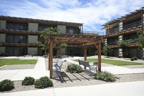 Moab apartment for rent - a patio with chairs and a pergola in front of an apartment building