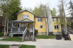 Park City apartment for rent - the front of a yellow house with a porch and stairs