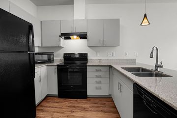 Salt Lake City apartment for rent - A black refrigerator stands in a kitchen with white cabinets and a black oven.