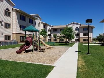 Vernal apartment for rent - a playground with a slide in front of an apartment building