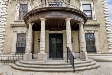 Buffalo apartment for rent - A large, old building with a black door and a balcony.