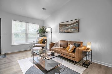 Buffalo apartment for rent - A living room with a brown couch, a glass coffee table, and a painting on the wall.