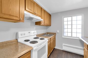 Lockport apartment for rent - A kitchen with a white stove and wooden cabinets.