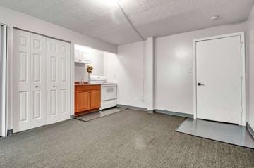 Niagara Falls apartment for rent - A kitchen area with a white fridge, a wooden cabinet, and a white oven.