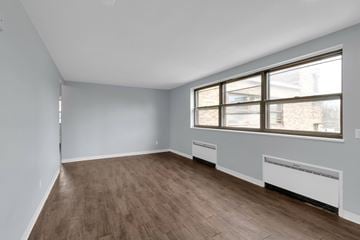 Buffalo apartment for rent - A room with wooden flooring and a window with a view of a building outside.