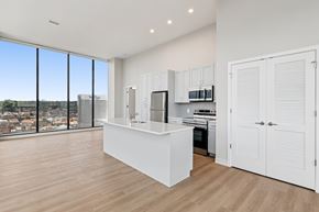 Cincinnati apartment for rent - A kitchen with white cabinets and a large window overlooking a cityscape at 7 West 7th Apartments, Cincinnati, 45202