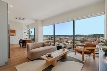 Cincinnati apartment for rent - A living room with a couch, chair, and table with a view of the city.