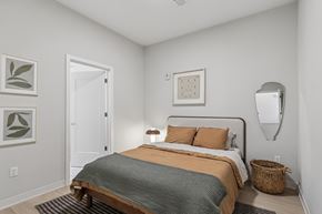 Pittsburgh apartment for rent - A bedroom with a bed, pillows, a basket, and a mirror at LiveWell Apartments, Pittsburgh 15222