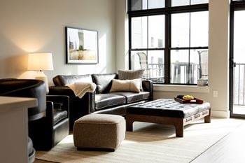 A black leather couch with a white throw blanket on it.