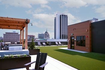 A wooden pergola is on a patio with a bench and a planter