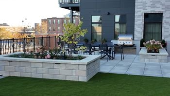 A patio with a table and chairs and a planter box with flowers.