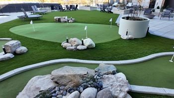 A miniature golf course with a white flag on the green.