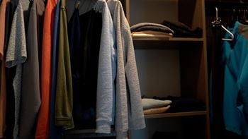Clothes hanging on a rack in a closet.