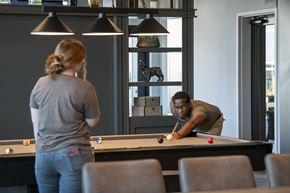 Fort Wayne apartment for rent - A man and a woman playing pool in a room. at The Pearl, Fort Wayne, IN