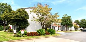 Huntsville apartment for rent - A tree with red flowers in front of a grey building.