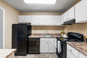 Mobile apartment for rent - A kitchen with black appliances and white cabinets.