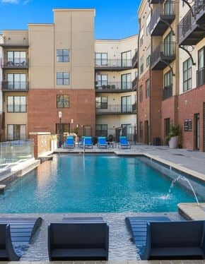 Tuscaloosa apartment for rent - A pool surrounded by a brick building and lounge chairs.