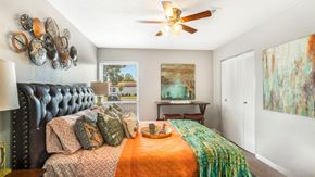 Huntsville apartment for rent - A bedroom with a black headboard and a bed with orange and green bedspread.