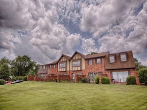 Tuscaloosa townhouse for rent - A large house with a red brick exterior and a green lawn in front.