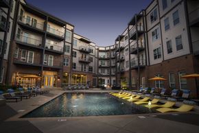 Madison apartment for rent - A swimming pool surrounded by yellow sun loungers in front of apartment buildings.