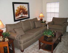 Tuscaloosa townhouse for rent - A living room with a brown couch, a brown armchair, a coffee table, and a framed picture of a tree.