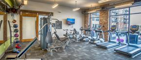 Tuscaloosa apartment for rent - a gym with cardio machines and weights on a brick wall