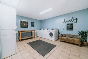 Mobile apartment for rent - A laundry room with a washer and dryer, a bench, and a fan.