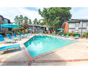 Flowood apartment for rent - a resort style pool with blue chairs and umbrellas