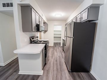 Riverside apartment for rent - A kitchen with a black refrigerator and white countertops.