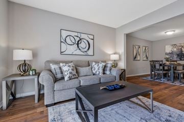 Pelham apartment for rent - A modern living room with a grey couch, a coffee table, and a dining table set in the background.