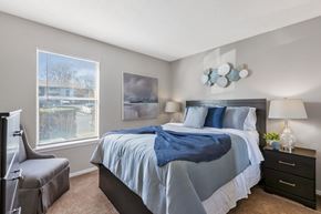 Pelham apartment for rent - A bedroom with a large bed and a window overlooking a parking lot.