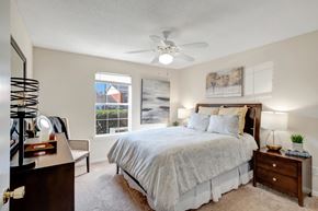 Tuscaloosa apartment for rent - A bedroom with a large bed, a dresser, and a ceiling fan.