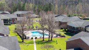Tuscaloosa apartment for rent - A swimming pool is surrounded by houses and trees.