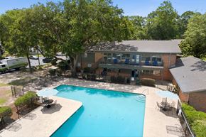 Mobile apartment for rent - A swimming pool surrounded by trees and a building.