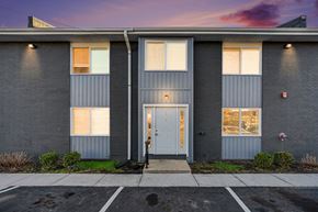 Raytown apartment for rent - A grey building with a white door and windows.