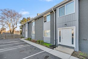 Raytown apartment for rent - A grey building with a white door and windows.