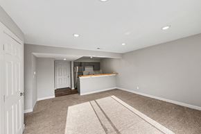 Warrensburg apartment for rent - A spacious room with a carpeted floor and a bar area in the background.
