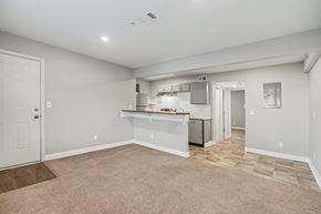 Raytown apartment for rent - A spacious room with a kitchenette and a door leading to another room.