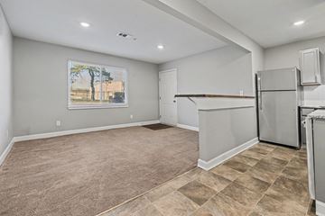 Raytown apartment for rent - A spacious kitchen with a refrigerator and a painting of a tree on the wall.