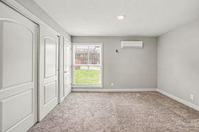 Independence apartment for rent - A room with a carpeted floor and a window showing a fence and a building outside.