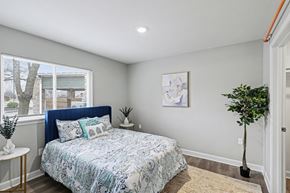 Kansas City apartment for rent - A bedroom with a bed, a plant, and a painting on the wall at Mayfair Apartments, Kansas City