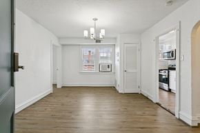 Newport News apartment for rent - A large empty room with a chandelier and a kitchen in the background. at Shipyard Shores Apartments, Newport News, 23607